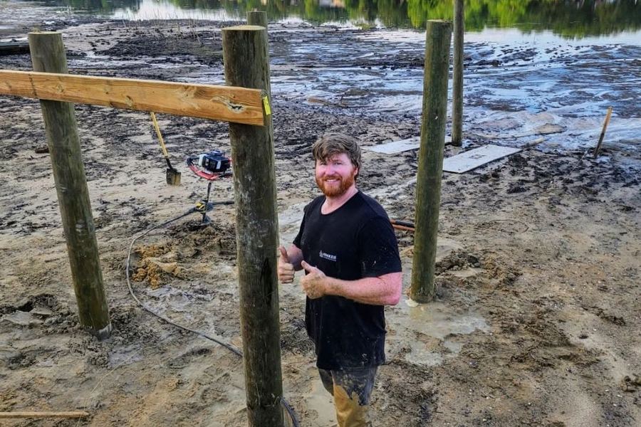 Sam Hemken on site between freshly set pilings during a lakeside dock build