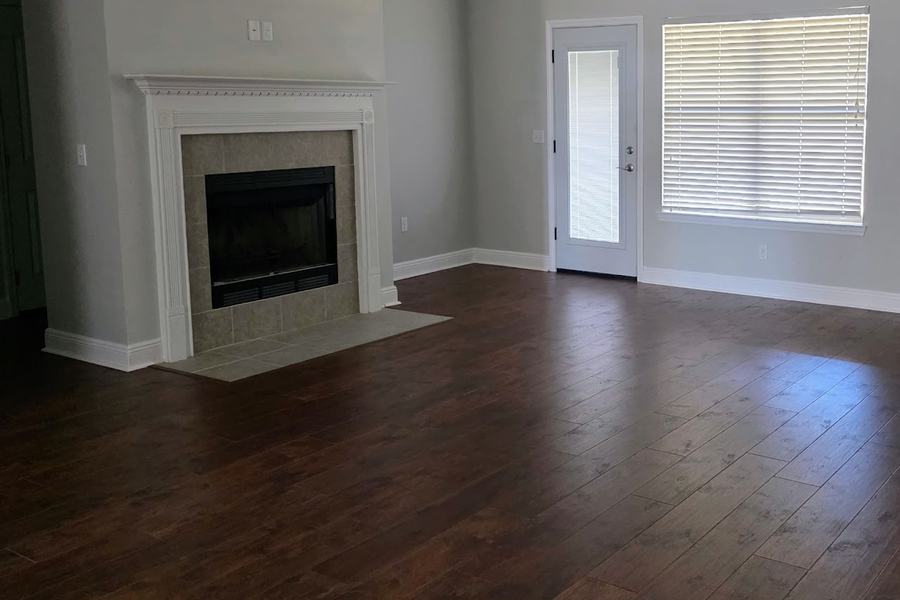 Living room with new dark plank flooring, fireplace, and a door to the patio