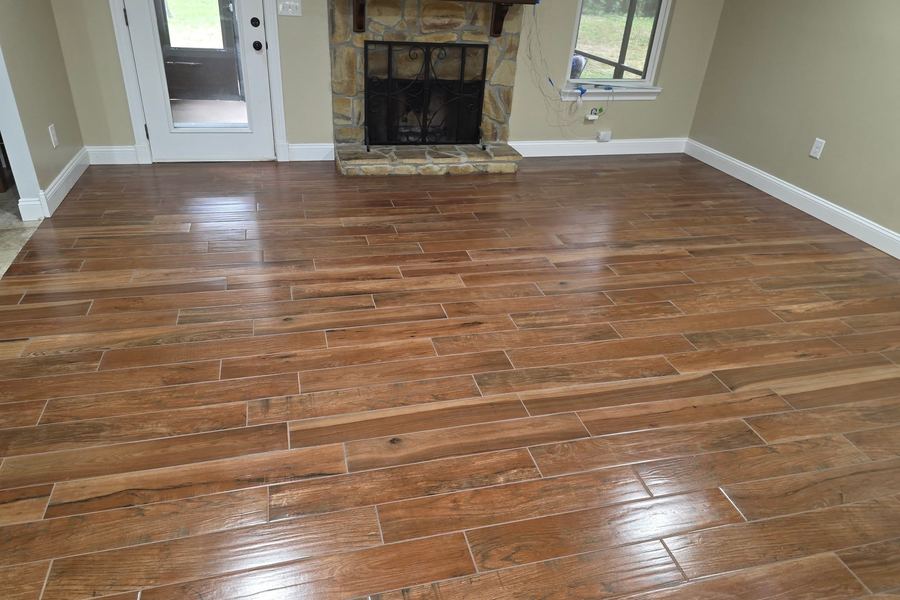 Wood-look porcelain tile laid through a living room with a stone fireplace