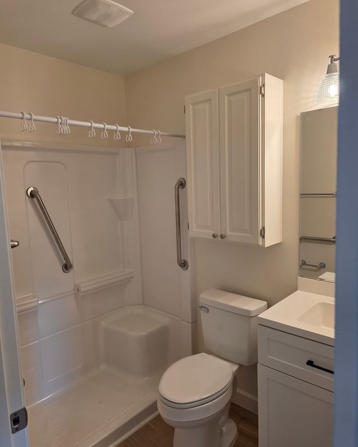Bathroom in the new build with a walk-in shower, grab bar, and wall cabinet
