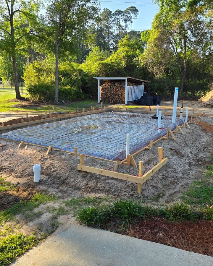 Slab formwork with wire mesh, vapor barrier, and plumbing stub-ups set before the concrete pour