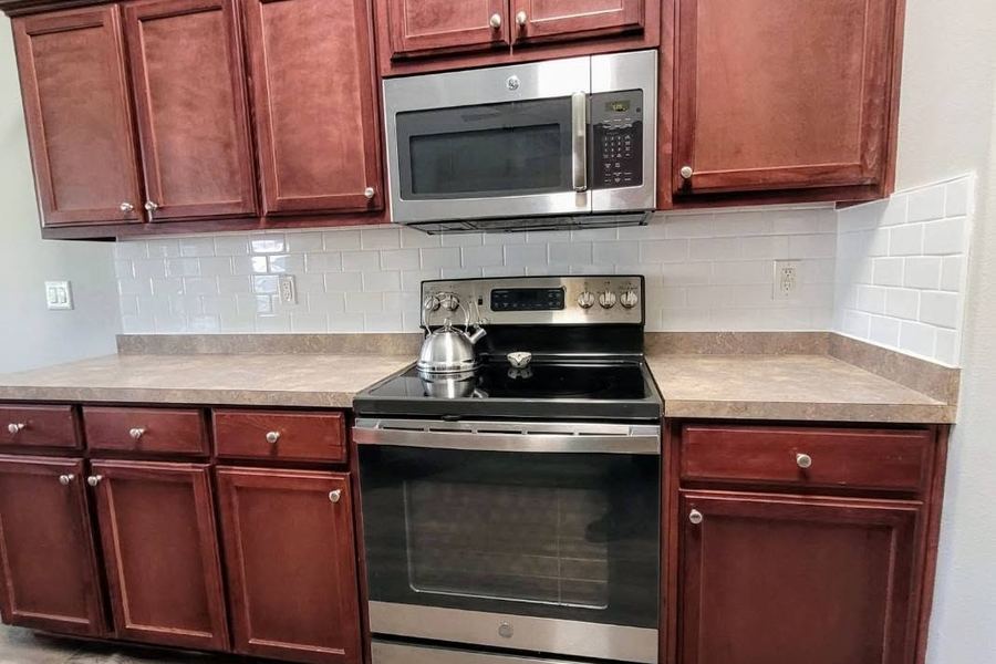 The same kitchen after: white subway tile backsplash and a new range