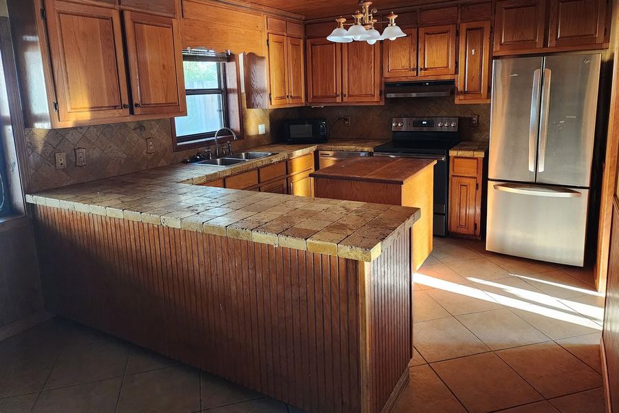 Kitchen before the remodel: oak cabinets, tile counters, and a wood ceiling