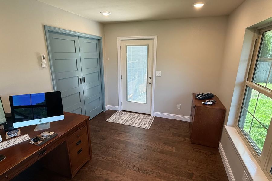 Home office built inside a former covered patio, with hardwood floors, new windows, and blue sliding doors