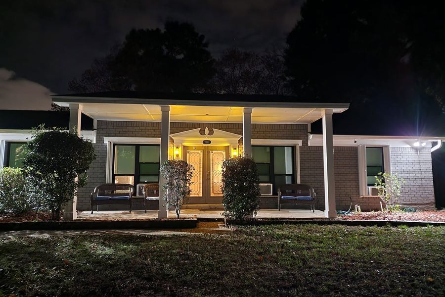 Front porch after the remodel, lit at night: new square columns, double doors, and painted brick